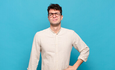 young man looking happy and friendly, smiling and winking an eye at you with a positive attitude