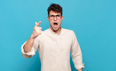 young man pointing at camera with an angry aggressive expression looking like a furious, crazy boss