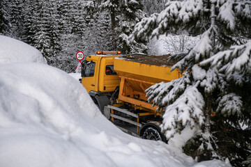 Snow plough truck cleaning a road through the mountains after winter massive snowfall