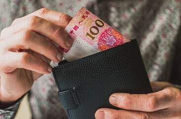 The man puts 100 yuan in his wallet.
