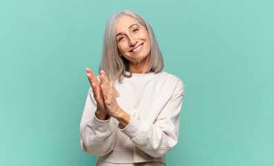 middle age woman feeling happy and successful, smiling and clapping hands, saying congratulations...