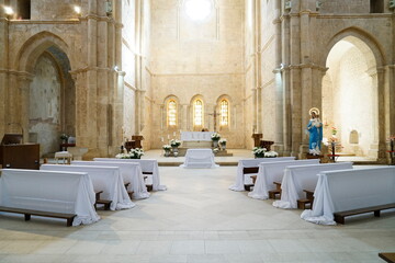 interno di una abbazia medievale con banchi coperti da teli bianchi pronti per la celebrazione...