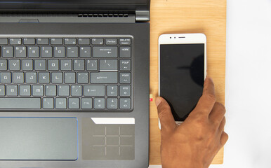 Top view of  black keyboard and the notebook have a mobile phone in hand,