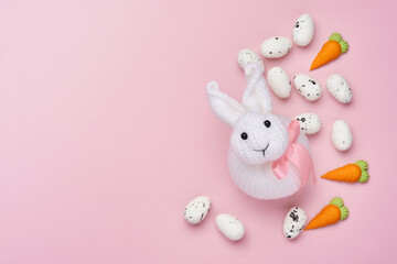 Easter spring greeting card with rabbit bunny, eggs and sweet carrot on pink background. Top view.