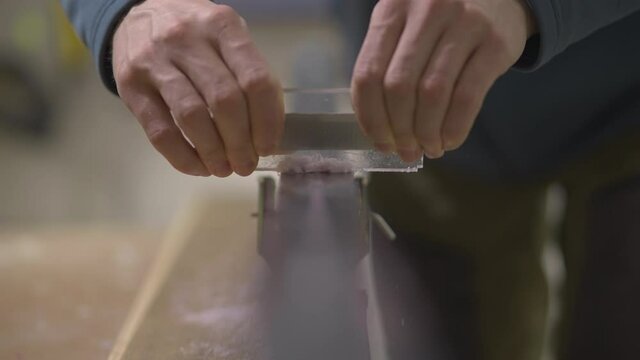 Scraping paraffin wax from ski during service, front view slow motion close up