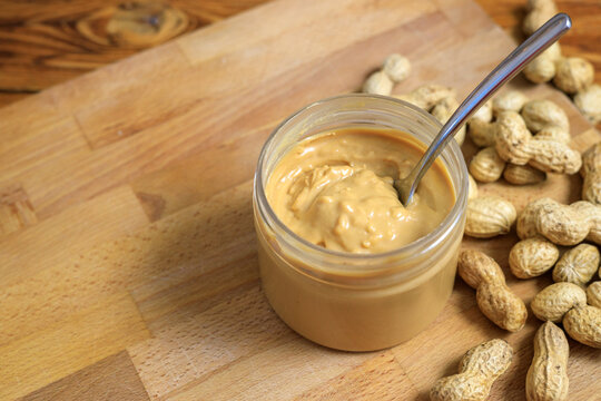 Opened jar with peanut butter and spoon in it