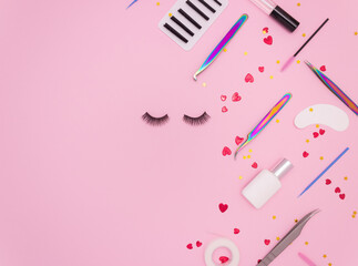 Eyelash extension tools, artificial eyelashes and red hearts on a pink background. Tools for the lashmaker. Top view, copyspace.