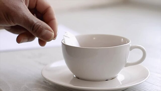 hand with cup of tea sitting on a table stock footage stock photo