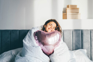  Woman sitting on bed with heart shaped balloons. Love. Valentine's day. Emotions.