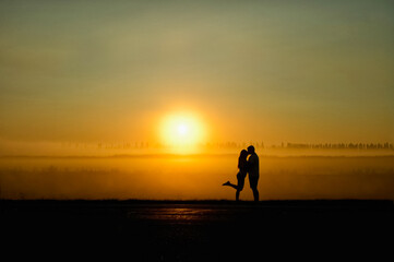 young couple of lovers kiss at sunset.