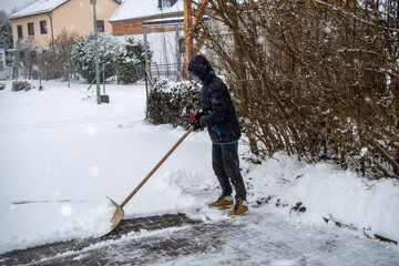 A teenager shovels snow from a driveway