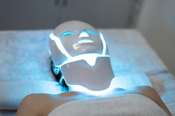 Woman is wearing cosmetic face photon mask. Health and beauty. Cosmetic procedure for woman face. Beauty laboratory. LED Facial Mask, Photon Therapy. Photo shows the different modes, colors