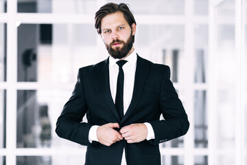 A successful businessman, dressed in an expensive suit, stands i