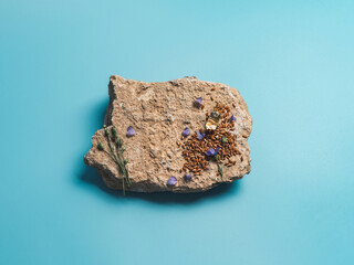 Flax seeds and flax oil on stone. Brown linen seeds, flaxseed oil and blue flax flowers on old gray rock over blue background. Copy space. Top view or flat lay. Mock up for cosmetic