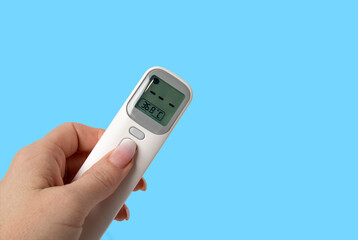 Woman's hand holds Thermometer Gun Isometric Medical Digital Non-Contact Infrared Sight Handheld Forehead Readings. Temperature Measurement Device isolated on blue background.