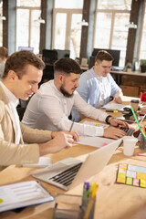 Concentrated. Young caucasian colleagues working together in a office using modern devices and gadgets. Look busy, attented, cheerful, successful. Concept of business, office, finance.