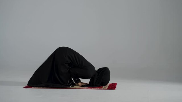 Asian Muslim woman in black HIJBAB praying white background
