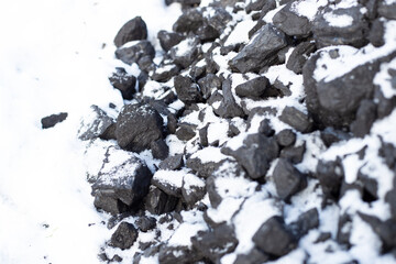 large pieces of coal under the snow. Fuel for the stove in winter. Heating a house in the countryside