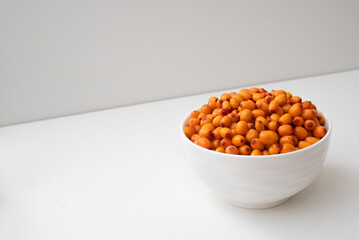 Deep white plate with sea buckthorn berries. Side view. On a two-tone background.