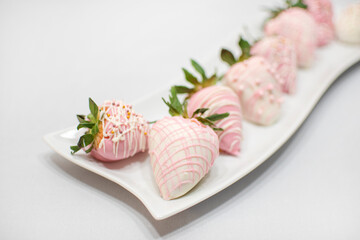 White Curve Rectangle Plate Full of Strawberry Covered Chocolate on White Fabric Background.