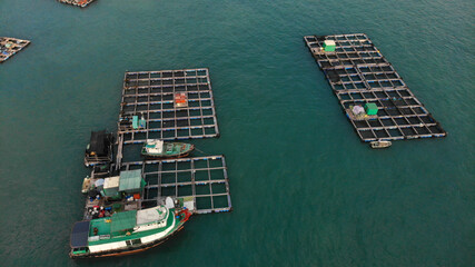 Fototapeta na wymiar Aerial view of fish farm on the water near Lamma Island, Hong Kong. A boat is sailing nearby.