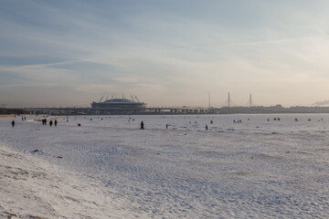 Scenic view on the stadium and people walking on the icy shore of the Finnish Gulf.