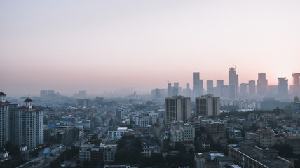 Guangzhou. There are small and tall houses and cars on the road below. The houses in the background are hidden in the fog. China