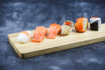 Japanese sushi on a rustic dark background. Sushi rolls, nigiri, maki, pickled ginger, wasabi, soy sauce. Sushi set on a table. Space for text. Top view. Sushi background. Asian or Japanese food frame