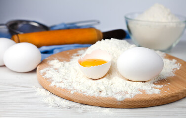 Baking ingredients: flour, eggs and rolling pin on a table. Close-up.