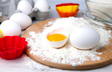Ingredients for baking muffins and cupcakes: flour, eggs and colourful silicone form on a table. Close-up.