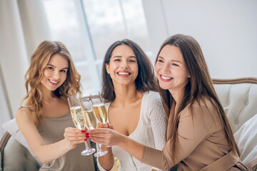 Three young girls having a hen party and drinking champagne