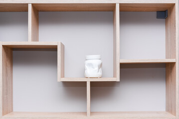 Wall mounted wood shelf with white ceramic vase. Home design composition in minimalist style.