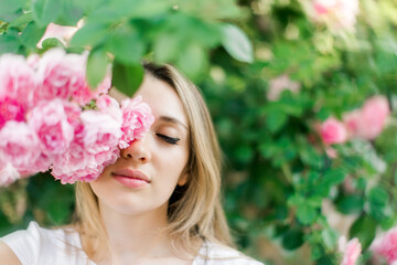 Fototapeta premium Blond lovely girl with blooming roses.Outdoors portrait,spring time.