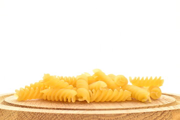 Obraz na płótnie Canvas Bright yellow uncooked Fusilli pasta on a wooden tray, close-up, isolated on white.