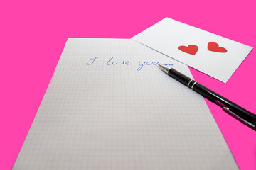 love letter, pen and envelote vith little paper hearts on pink background