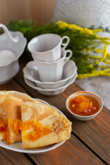 Thin pancakes with orange jam or marmalade on wooden background. Tasty breakfast. Maslenitsa.