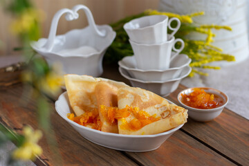 Thin pancakes with orange jam or marmalade on wooden background. Tasty breakfast. Maslenitsa.
