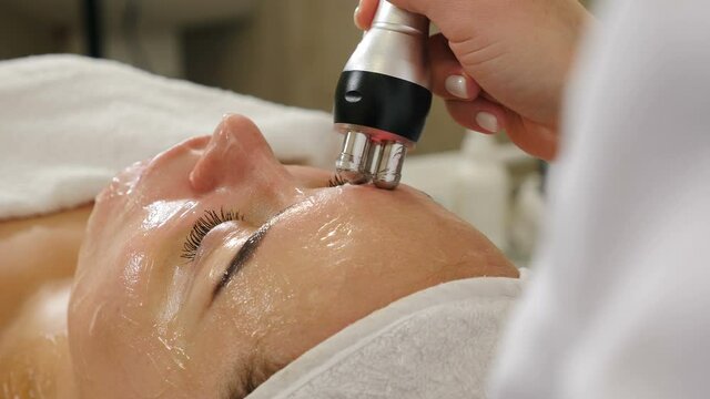 Cosmetologist making biolifting rf-lifting procedure. Rejuvenating skin, preventing aging, woman getting stimulating beauty facial treatment. hardware cosmetology in modern clinic. 4 k video