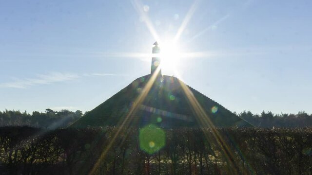 Medium shot Time lapse of sun appearing behind obelisk on Austerlitz Pyramid. The Piramide van Austerlitz is a monument built in 1804 as a tribute to Napoleon Bonaparte.
