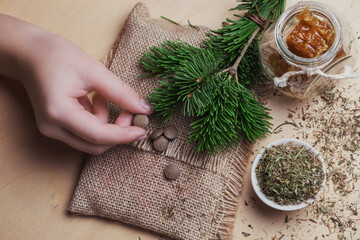 Obraz na płótnie Canvas Tablets from natural ingredients in a child's hand, phyto pharmacy. A jar of honey, a bouquet of pine branches and herbal tea. Elements of traditional medicine.