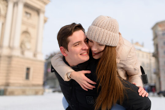 Young guy and girl in winterwear enjoying snowfall