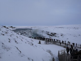 frozen waterfall with people in Iceland in winter