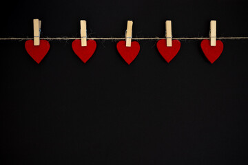 Red heart hanging on the clothesline, on black background. Valentines Day