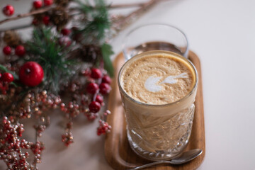 cup of coffee latte or cappuccino with a glass of water on a tray. near decorative red branches. interior, cozy