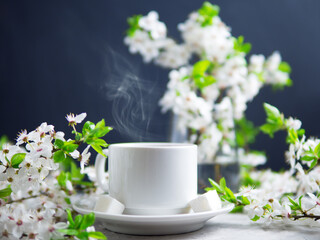 A cup of tea on the table with spring cherry blossoming branches