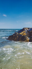Seascape of rocky beach. Sea waves crash and splash on rocks. View of the sea, ocean. Natural soft blue background. View of the sea, ocean. Rockaway Beach,