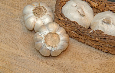 Healthy and wholesome food. 
Fresh garlic in a wicker basket on a wooden background.
Selective focus.
Top side view.