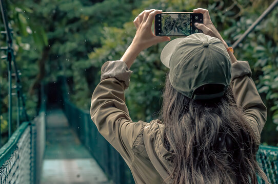 Woman taking a photo in the jungle on a bridge - Powered by Adobe