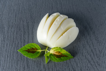 Boiled egg cut like a flower and green leaves on a gray background