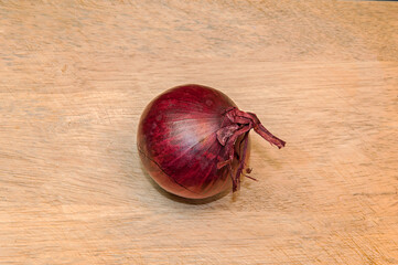 One red onion on light wooden table background with copy space for text.
Top view.